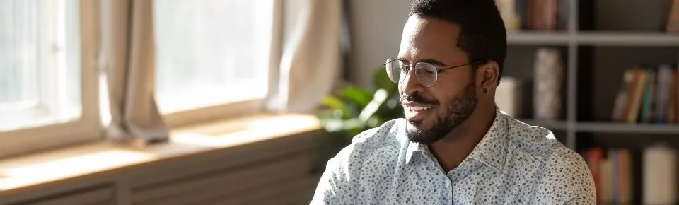 Un homme souriant travaille devant son ordinateur.